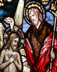 a stained glass window portraying Jesus holding a staff
